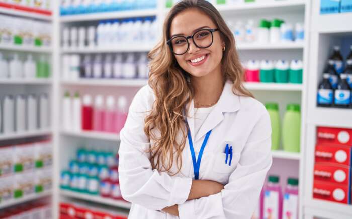 Apothekerin steht im Verkaufsraum und lächelt