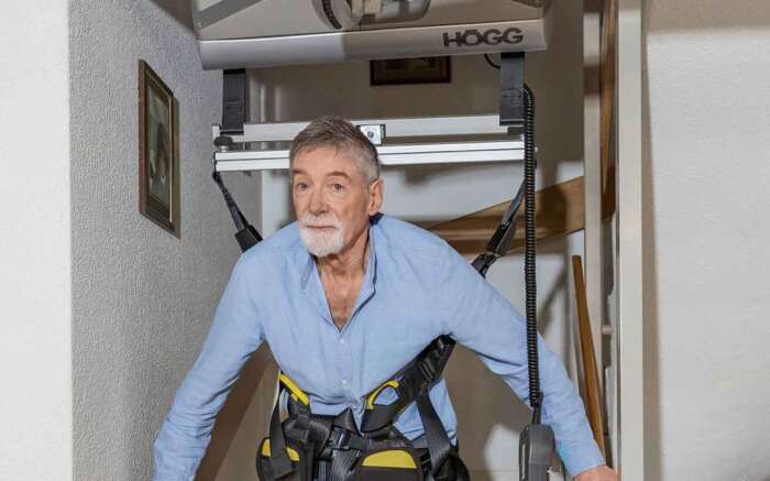 Heinz Bühlmann steigt mit Hilfe einer Tragekonstruktion die Treppe hinunter