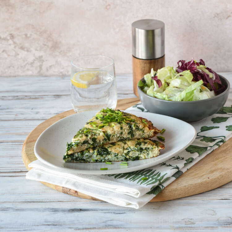Zu sehen ist ein Teller mit einem Stück Tortilla, daneben ein kleiner Salat und ein Glas Wasser