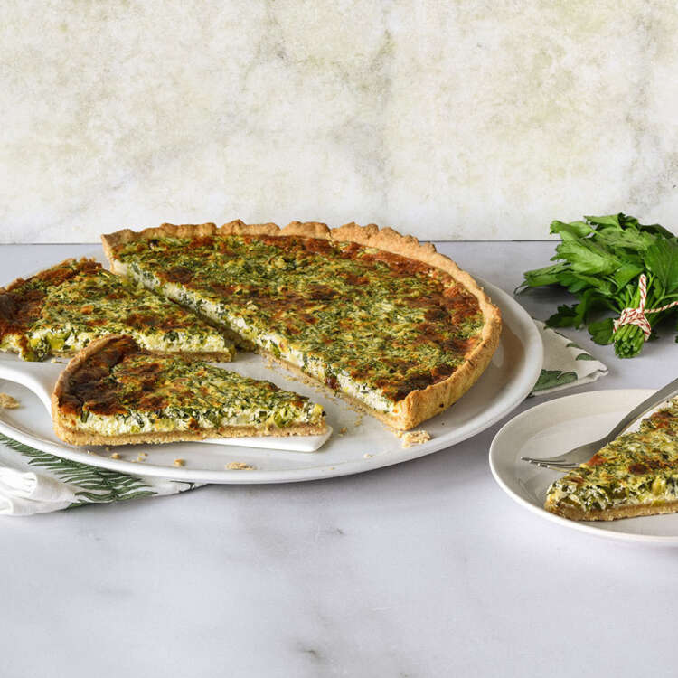 Auf einem grossen weissen Teller liegt eine Wähe, daneben ist ein Stück davon abgeschnitten auf einem kleinen Teller