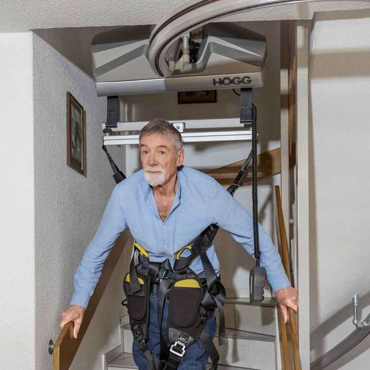 Heinz Bühlmann steigt mit Hilfe einer Tragekonstruktion die Treppe hinunter