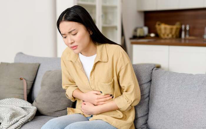 Eine Frau hält sich vornübergebeugt den Bauch