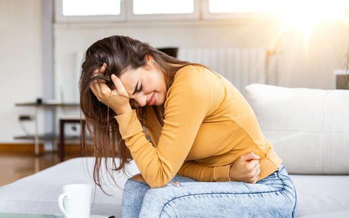 Eine Frau hält sich vornübergebeugt den Bauch