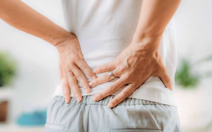 Ansicht auf einen Rücken, eine Person hält sich die Hände darauf