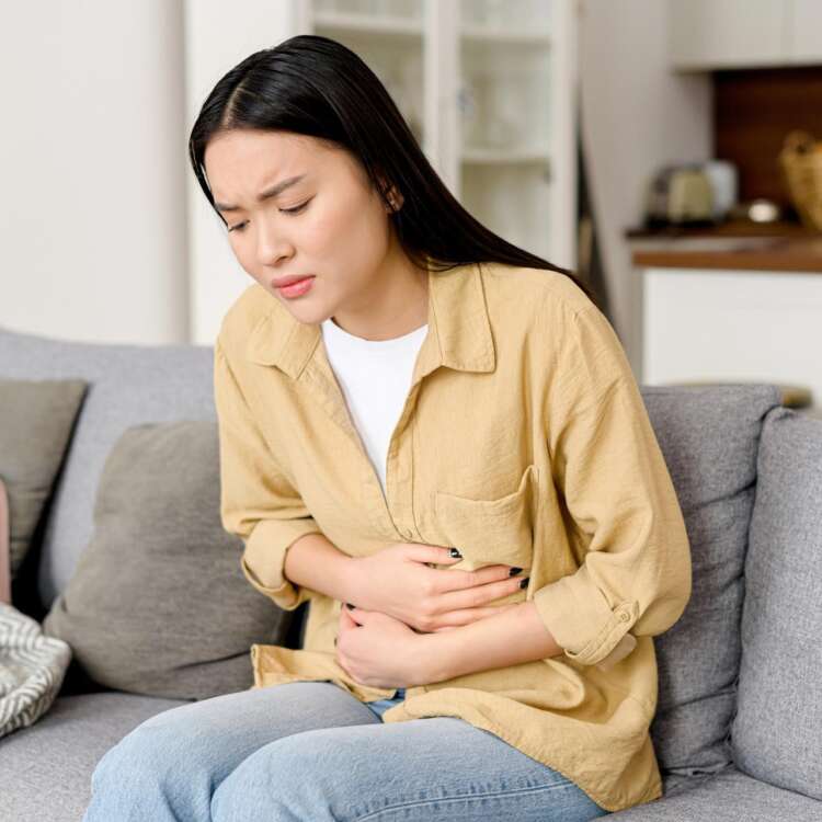 Eine Frau hält sich vornübergebeugt den Bauch