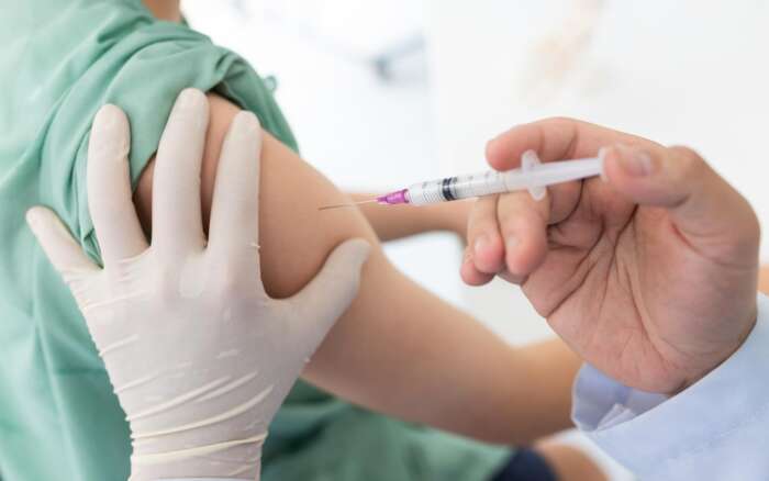 Eine Hand setzt eine Impfung am Oberarm an