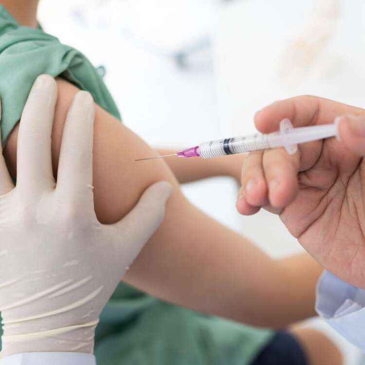 Eine Hand setzt eine Impfung am Oberarm an