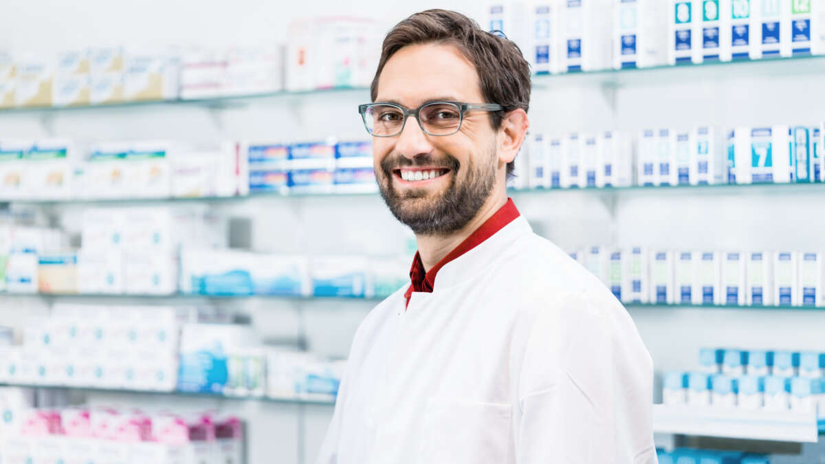 Apotheker steht in der Apotheke vor Regal mit Produkten