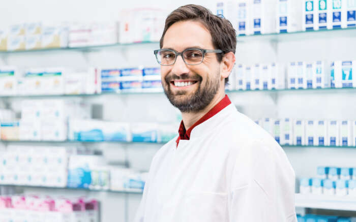 Apotheker steht in der Apotheke vor Regal mit Produkten
