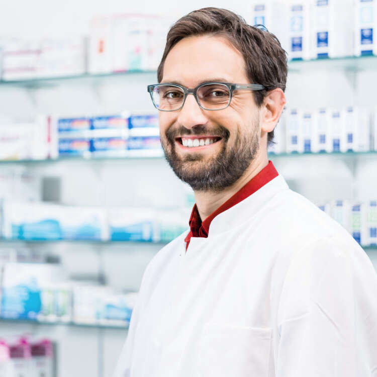 Apotheker steht in der Apotheke vor Regal mit Produkten